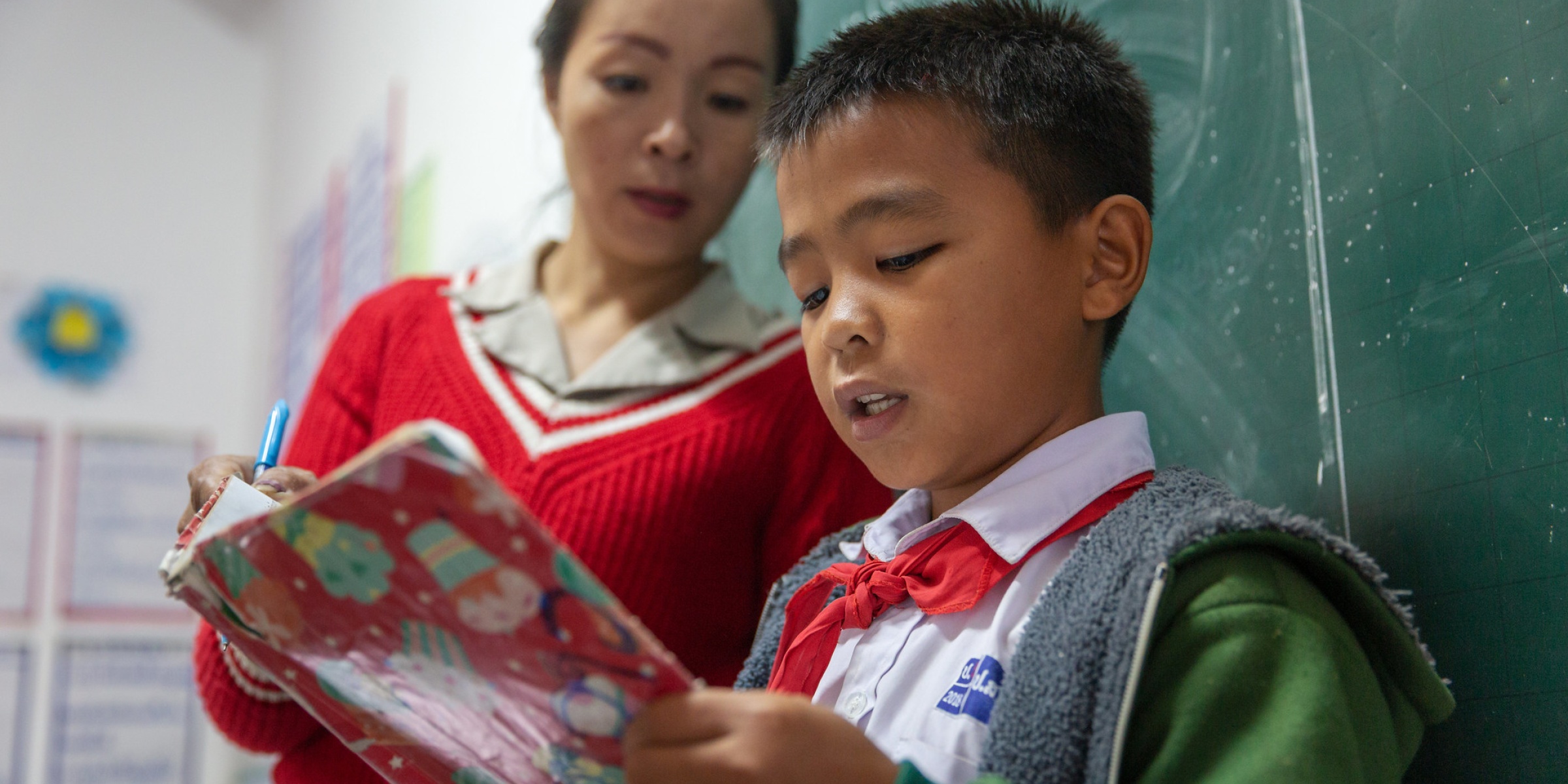 A fifth grade student reads aloud in front of the class while teacher Khammanh Ladavone looks on. Somsanouk Primary School, Pak Ou District, Lao PDR. Credit: GPE/Kelley Lynch